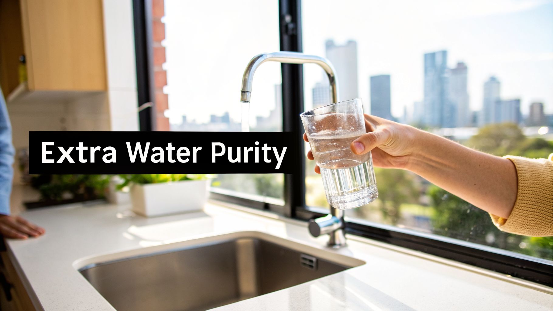 A hand holds a glass being filled with water from a modern kitchen tap with a city view.