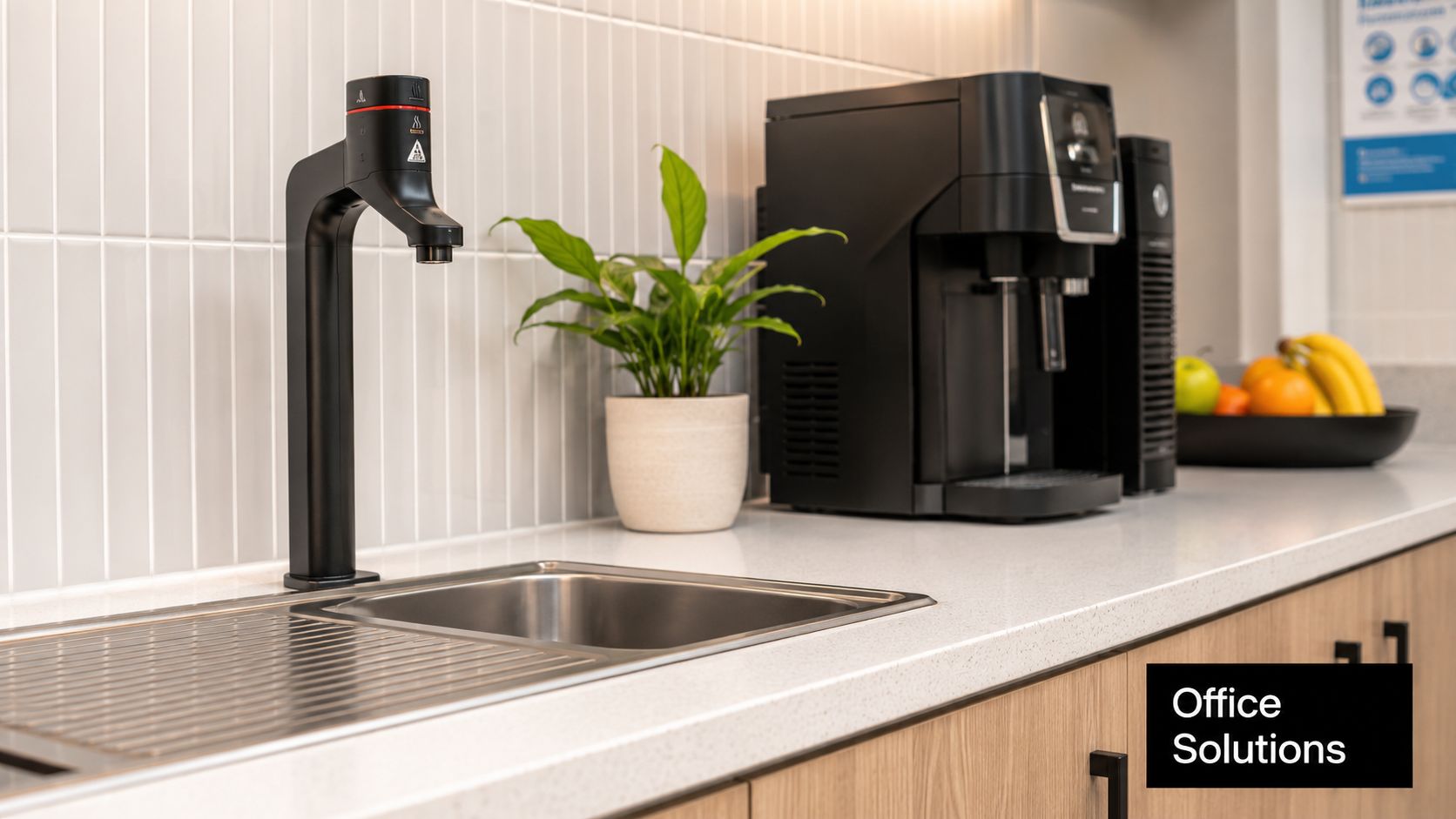 A sleek modern office kitchenette featuring a boiling water tap, coffee machine, and a fruit bowl.